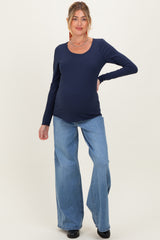 woman wearing a navy long sleeve maternity top and light blue wide-leg jeans, showing baby bump