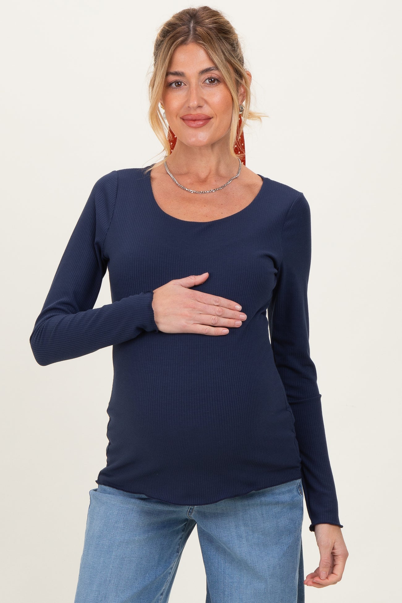 woman wearing a navy long sleeve maternity top and holding her baby bump