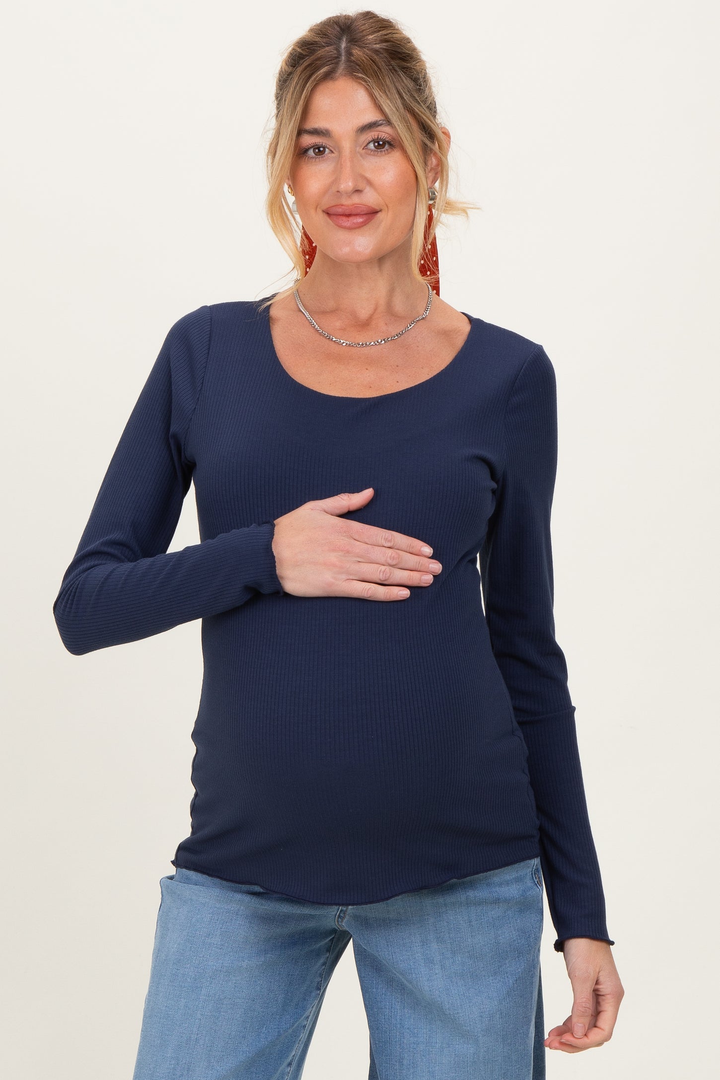 woman wearing a navy long sleeve maternity top and holding her baby bump