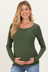 woman wearing a dark green long sleeve maternity top and holding her baby bump