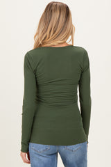 woman wearing a dark green long sleeve maternity top with fitted style and ruched sides