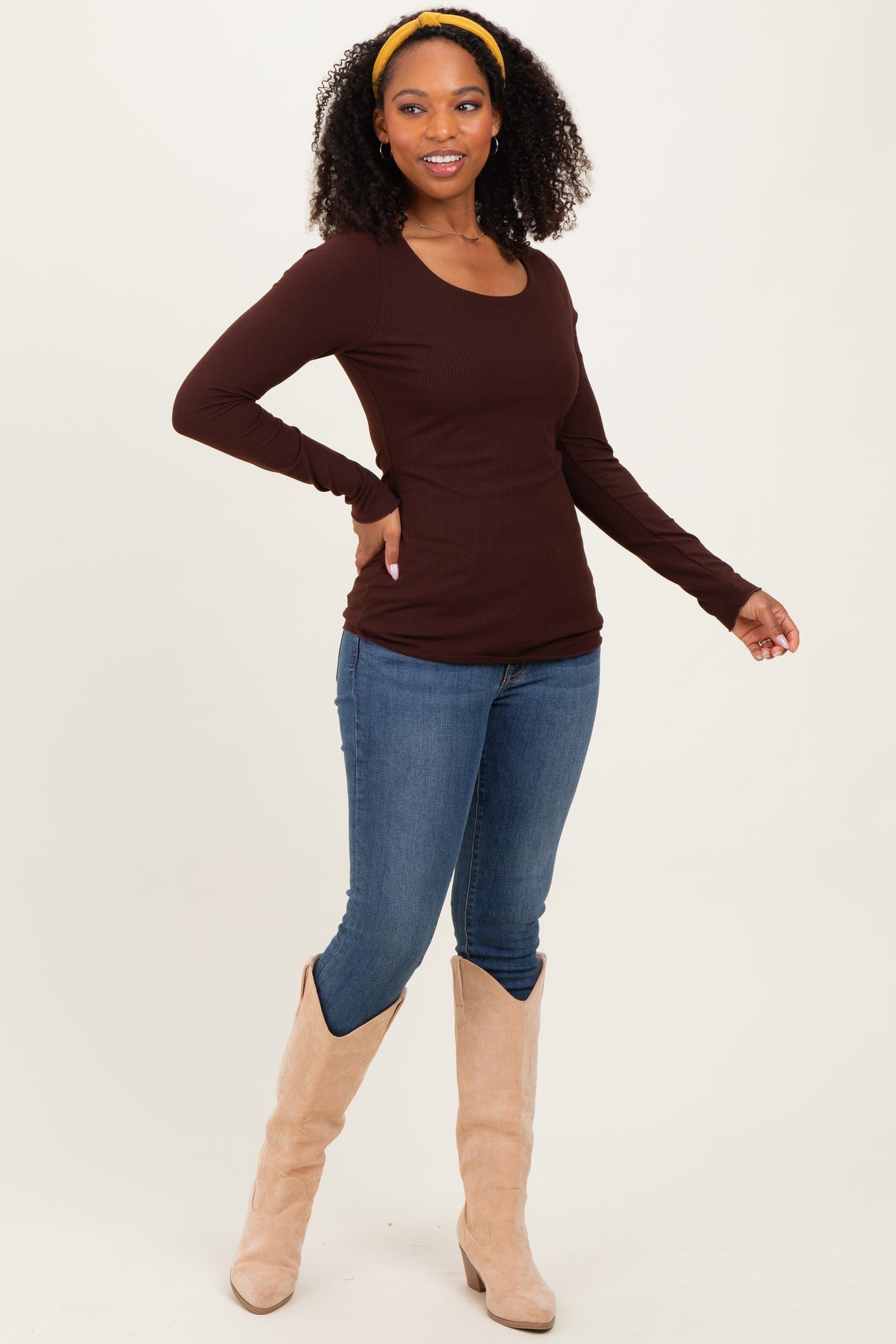woman wearing a brown long sleeve ribbed top paired with blue skinny jeans and beige knee-high boots