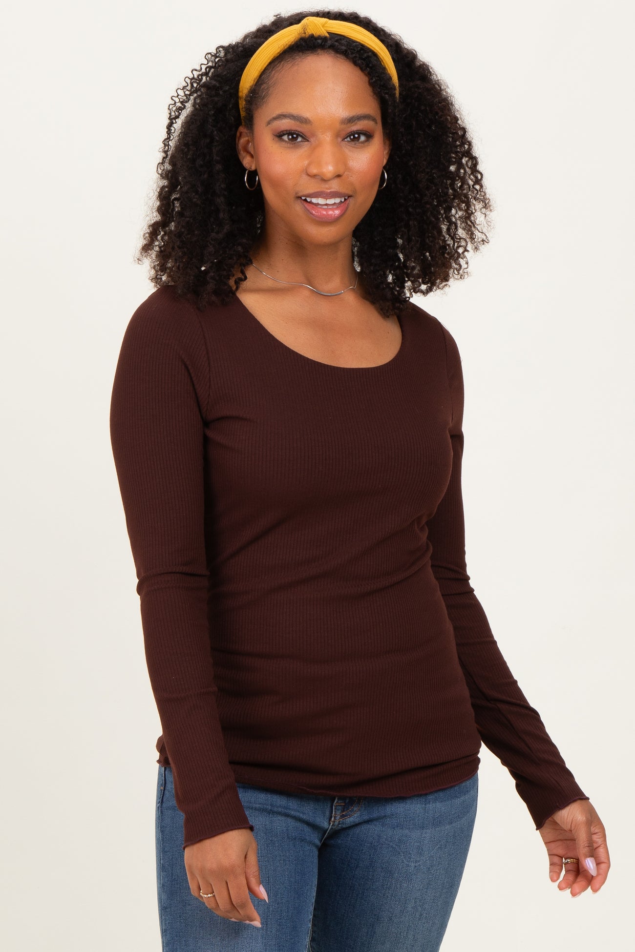woman wearing a brown long sleeve ribbed top with a scoop neckline and styled with a yellow headband
