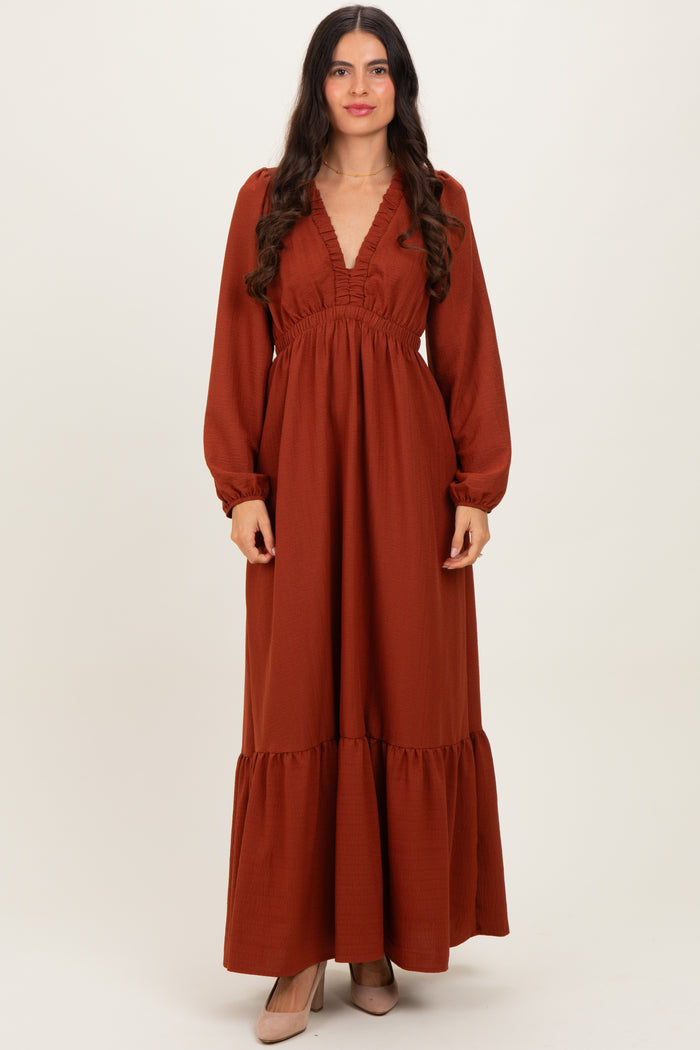 woman wearing a rust long sleeve maxi dress with a v-neck and ruffle details