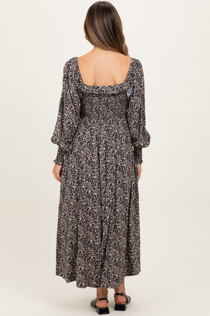 woman wearing a black floral maternity dress with puffed sleeves and a smocked back, showing her baby bump.