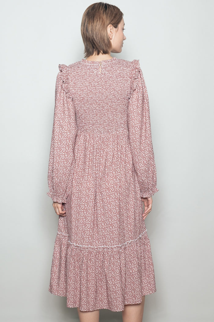 woman wearing a maroon floral long sleeve dress with ruffle details and a tiered skirt seen from the back