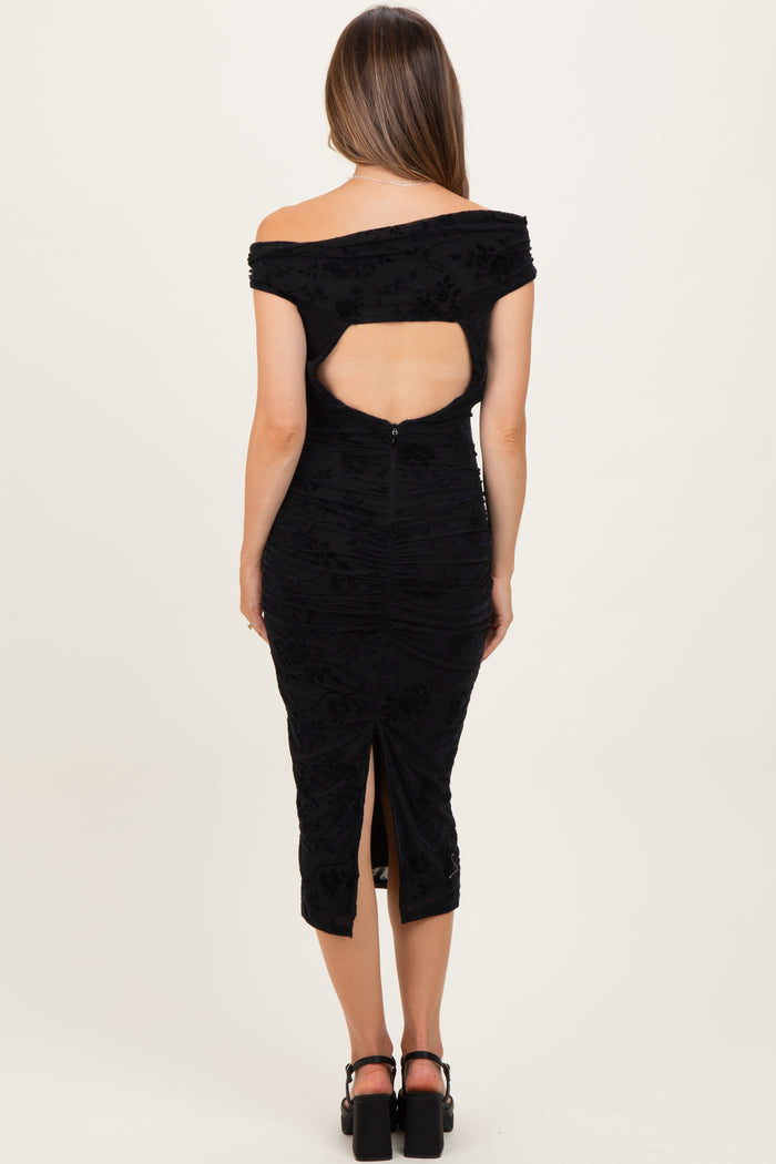 woman wearing a black off-the-shoulder maternity dress with a back cutout and a slit at the hem