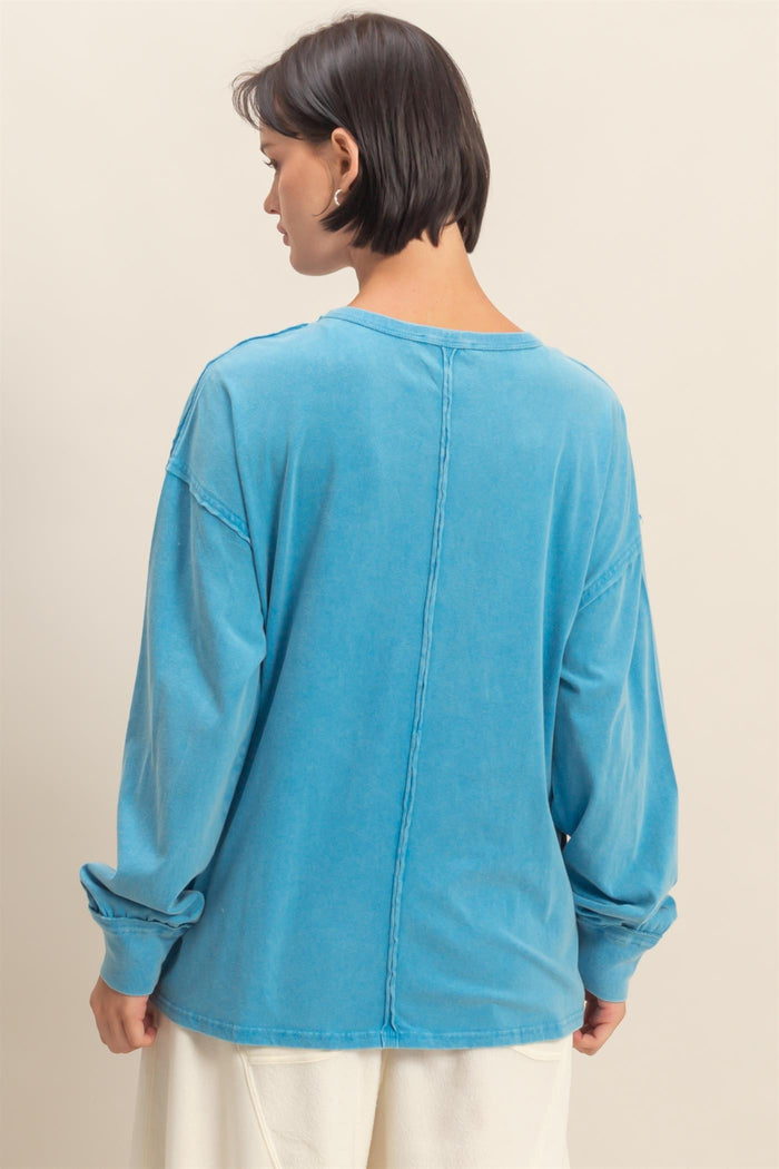 woman wearing a blue oversized long sleeve top with a relaxed fit and seam detail on the back