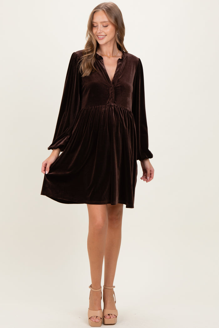 woman wearing a brown velvet maternity dress with long sleeves and a button-up front, featuring a flowing silhouette