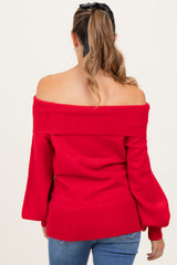 woman wearing a red off-the-shoulder maternity sweater with ribbed detailing and bell sleeves