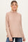 woman wearing a light brown maternity turtleneck top with a relaxed fit and a baby bump visible