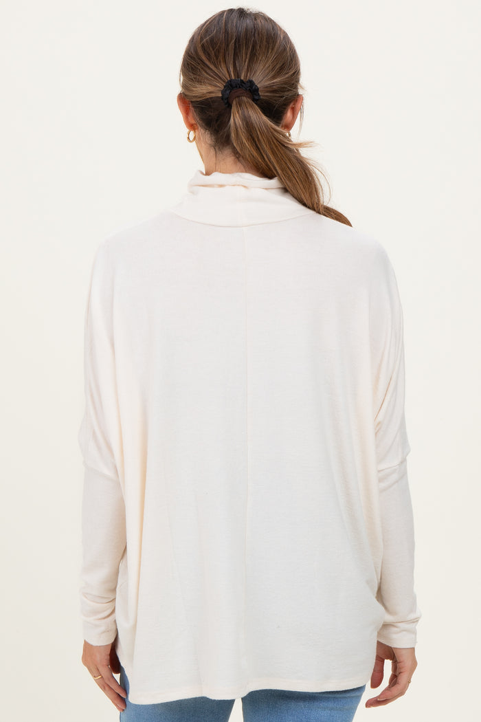 woman wearing a cream long sleeve maternity top, viewed from the back, with relaxed fit and draped neckline