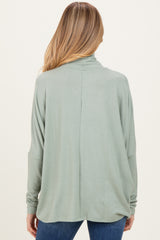 woman wearing a light green maternity top with a relaxed fit and long sleeves, viewed from the back