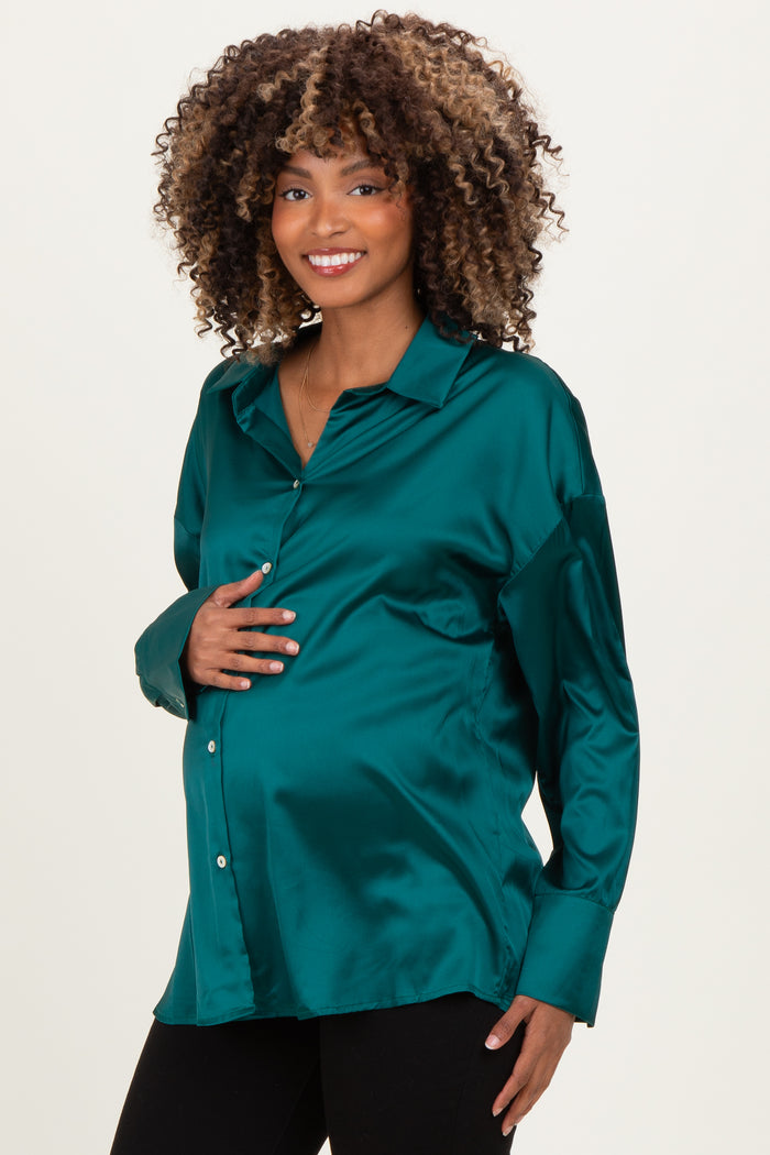 woman wearing a teal satin maternity blouse and holding her baby bump