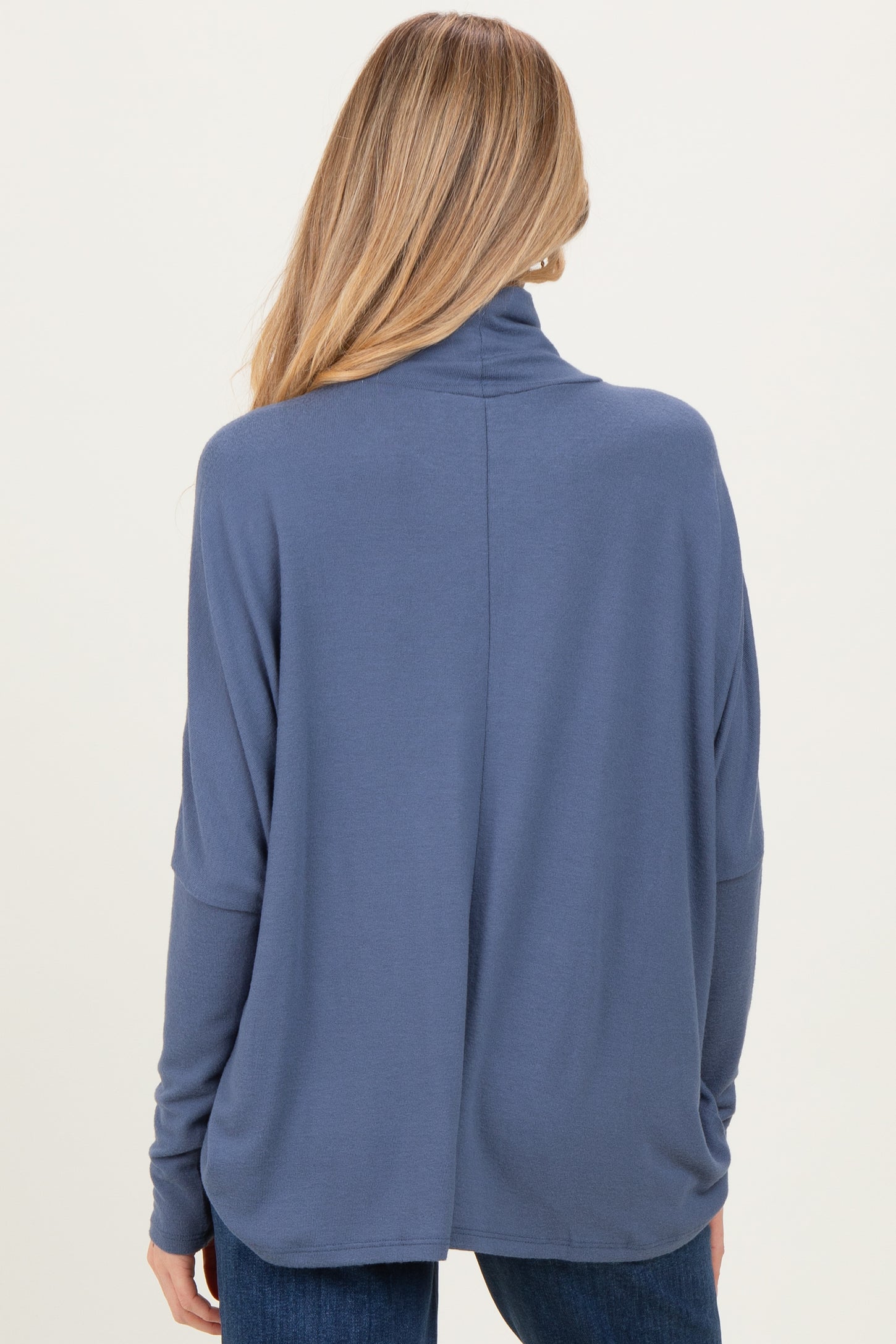 woman wearing a navy blue maternity top with a relaxed fit and turtle neckline, shown from the back