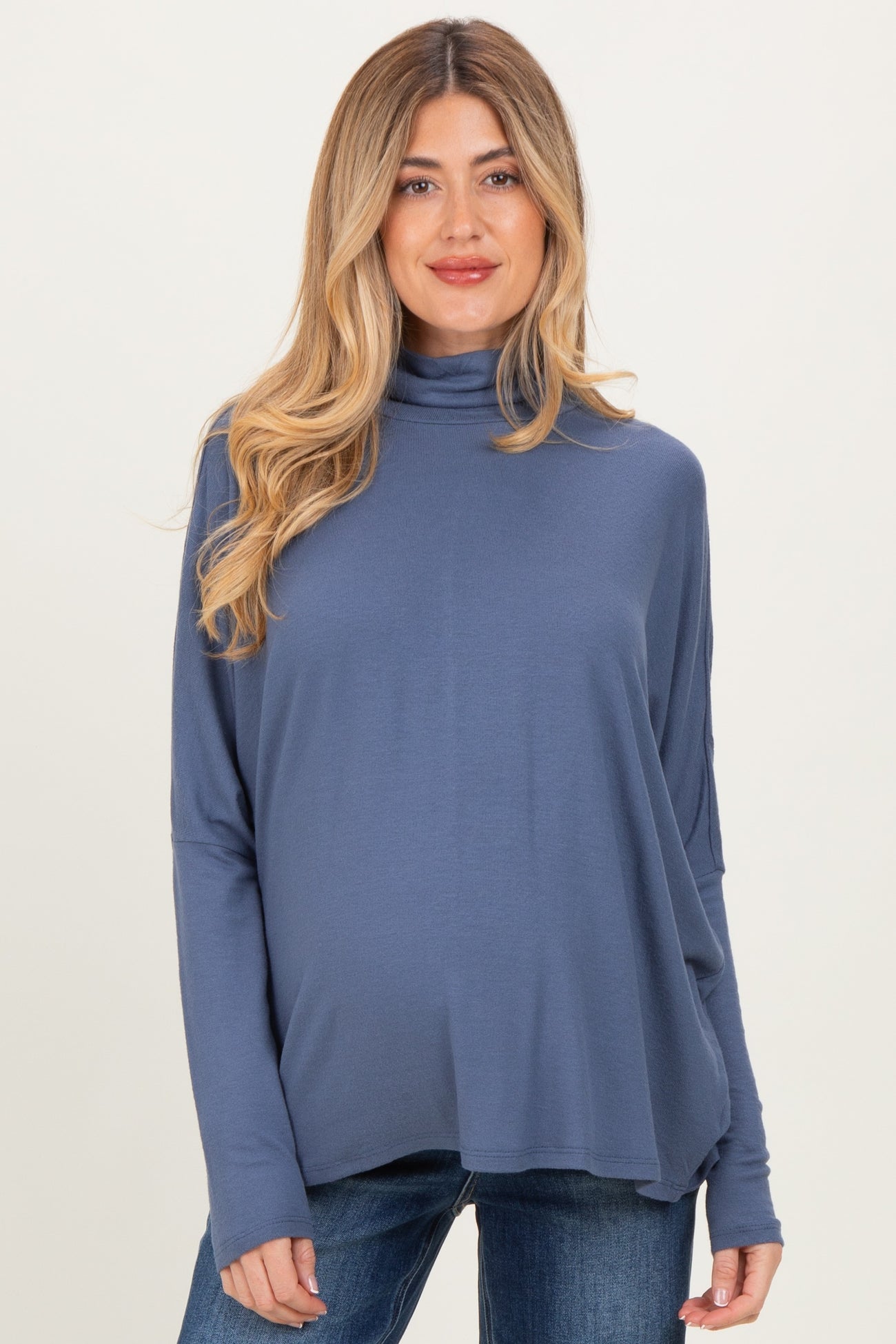 woman wearing a blue long sleeve maternity top with a turtleneck and visible baby bump