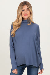 woman wearing a blue long sleeve maternity top with a turtleneck and visible baby bump