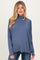 woman wearing a blue long sleeve maternity top with a turtleneck and visible baby bump