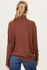 woman wearing a rust-colored maternity sweater with a relaxed fit and high collar, viewed from the back