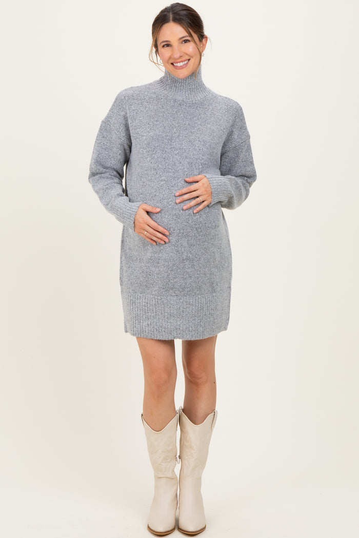 woman wearing a gray maternity sweater dress with a high neck and holding her baby bump