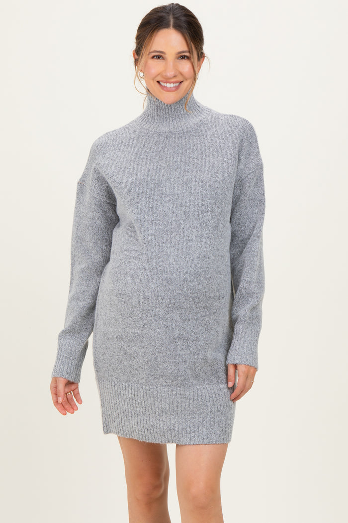 woman wearing a gray maternity turtleneck sweater dress with long sleeves and side slits, showing her baby bump