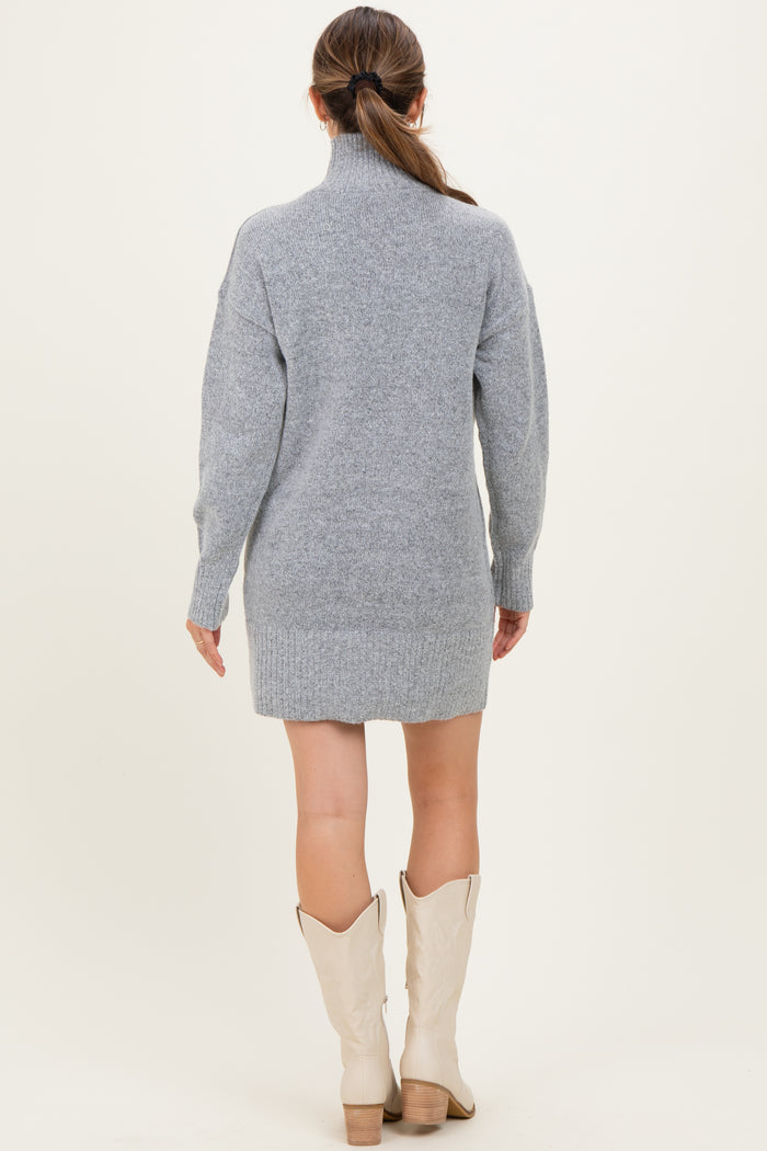 woman wearing a gray maternity sweater dress with a turtleneck and long sleeves, styled with cream boots