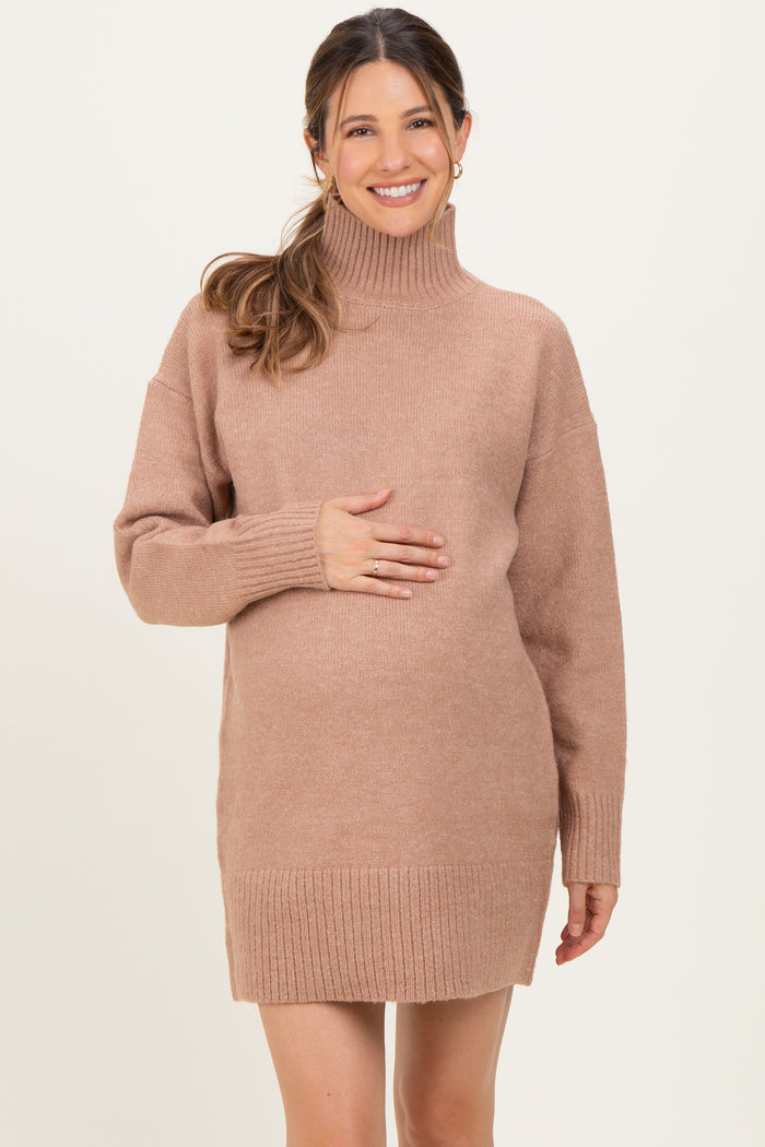 woman wearing a brown oversized maternity sweater dress and holding her baby bump