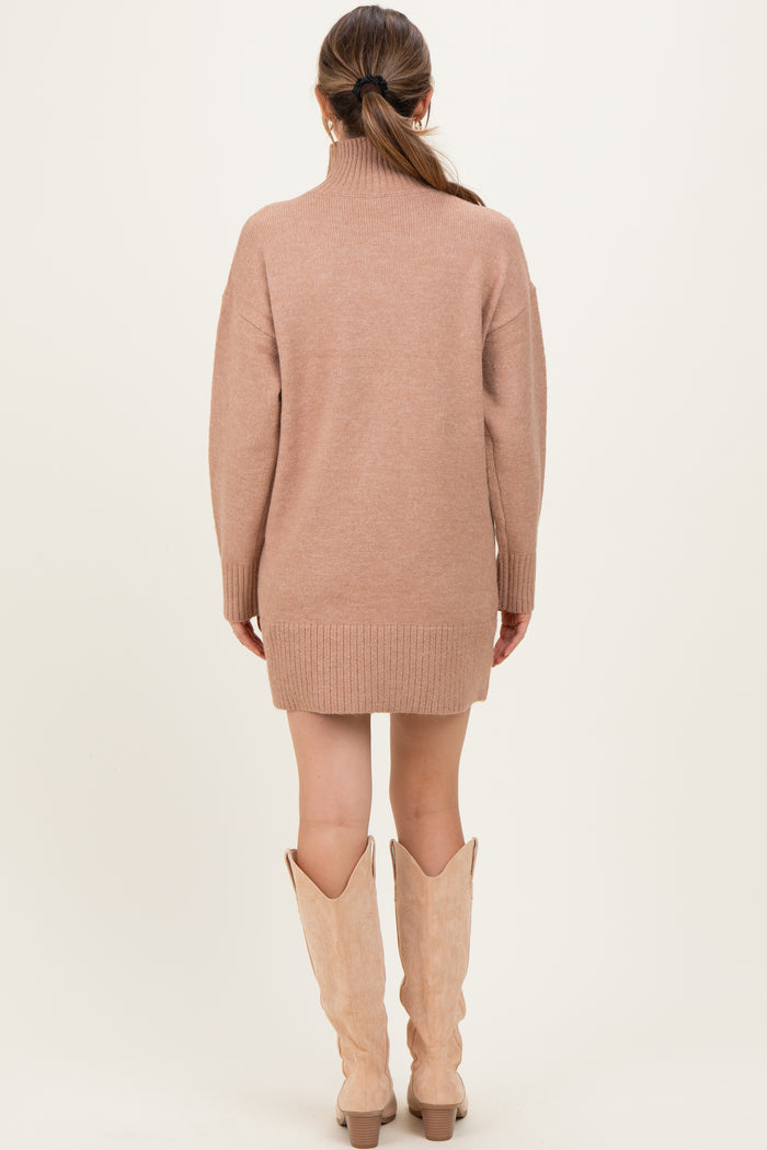 woman wearing a beige maternity sweater dress with a high collar and ribbed hem, showcasing a relaxed fit
