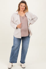 woman wearing a light brown maternity plus v-neck top, layered with a cream button-up shirt and blue jeans