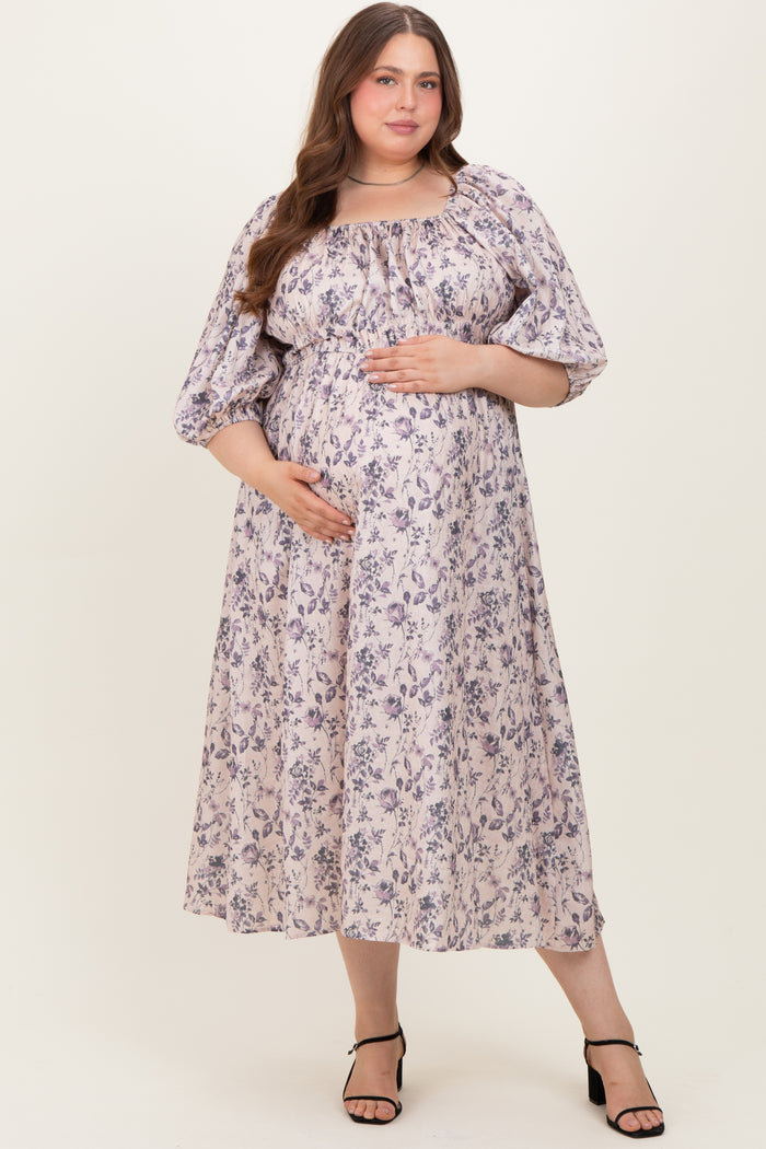 woman wearing a floral print maternity dress with puff sleeves and a baby bump, standing and smiling