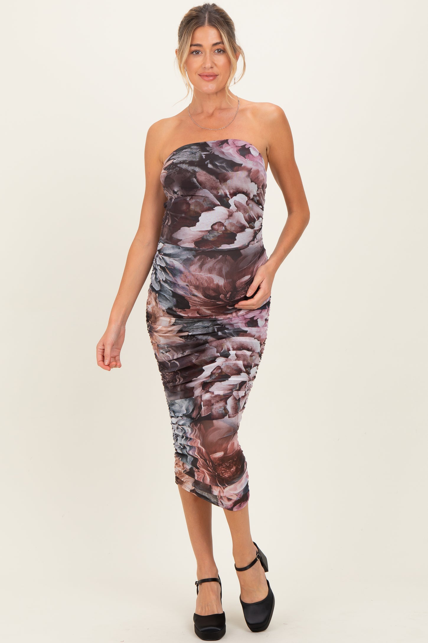 woman wearing a dark floral print strapless maternity dress with a fitted silhouette and side ruching, showing a baby bump