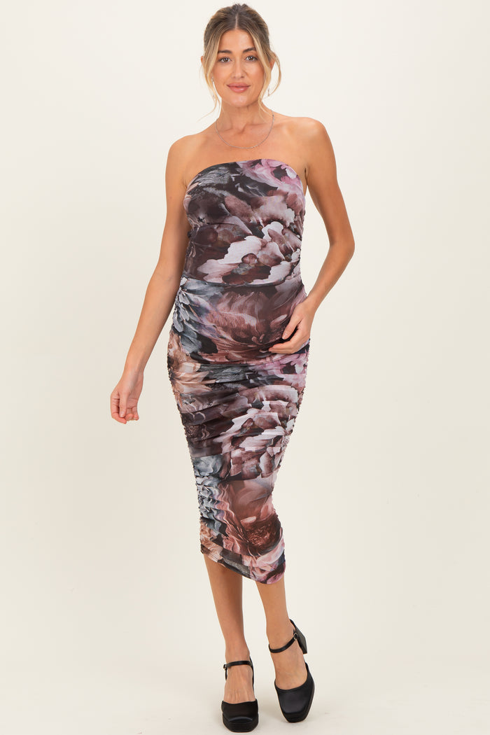 woman wearing a dark floral print strapless maternity dress with a fitted silhouette and side ruching, showing a baby bump