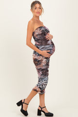 woman wearing a strapless bodycon maternity dress with a floral print and holding her baby bump