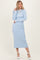 woman wearing a light blue ribbed midi dress with a tie neckline and long sleeves