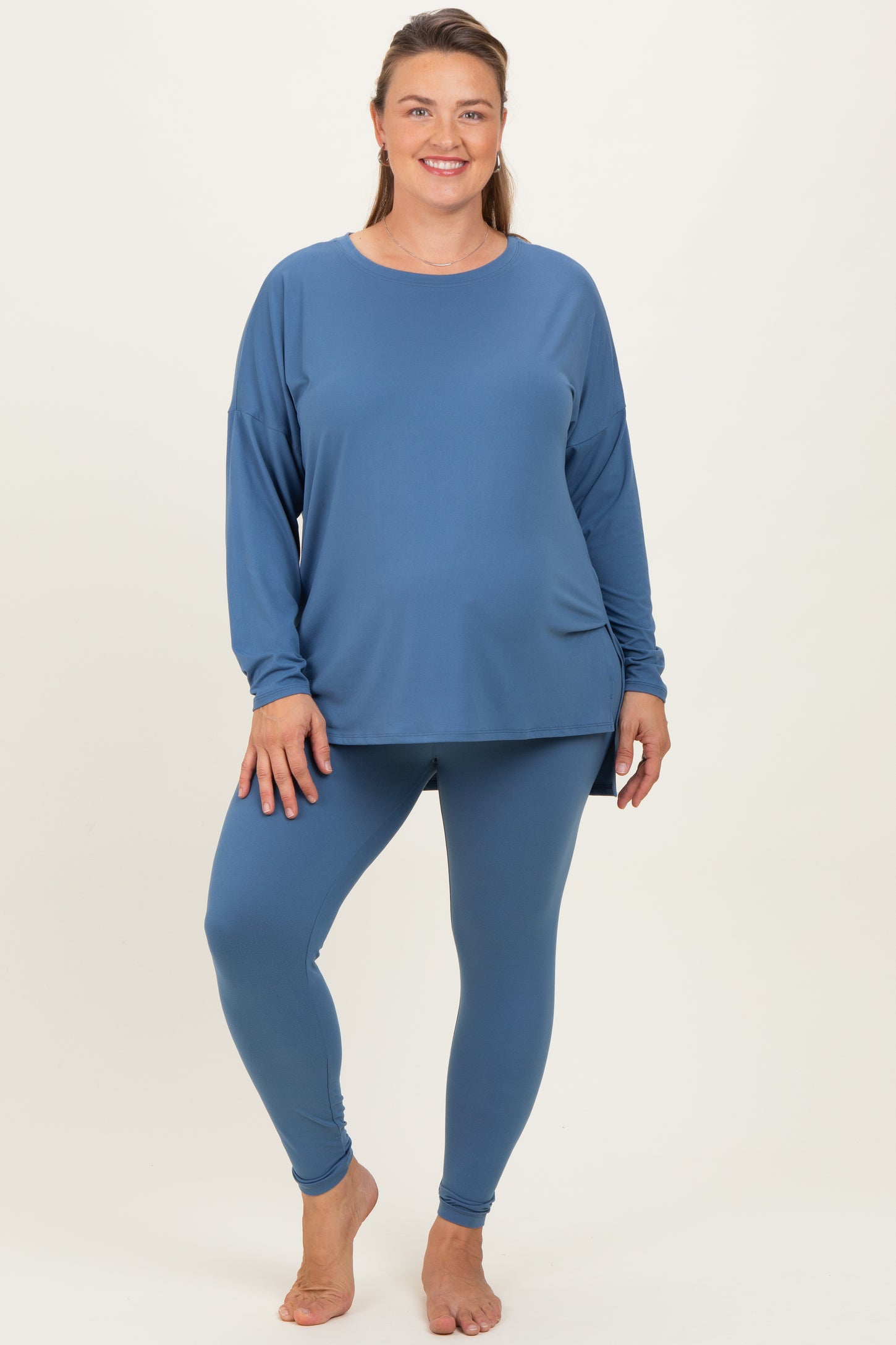woman wearing a blue long sleeve maternity top and matching leggings, showcasing a comfortable maternity plus outfit