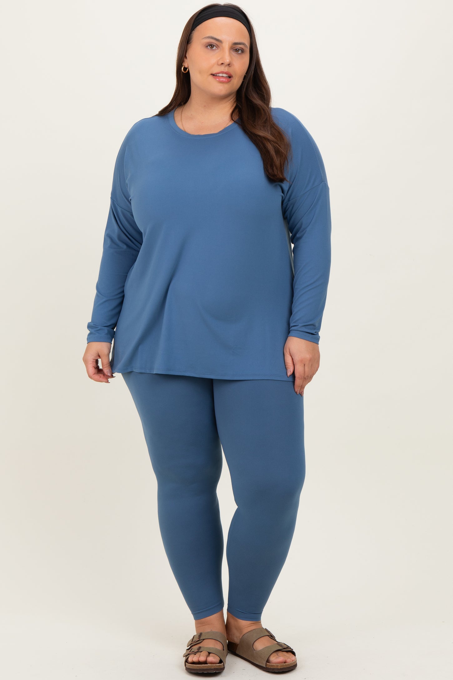 woman wearing a dark blue long sleeve top and matching leggings, standing with a relaxed pose