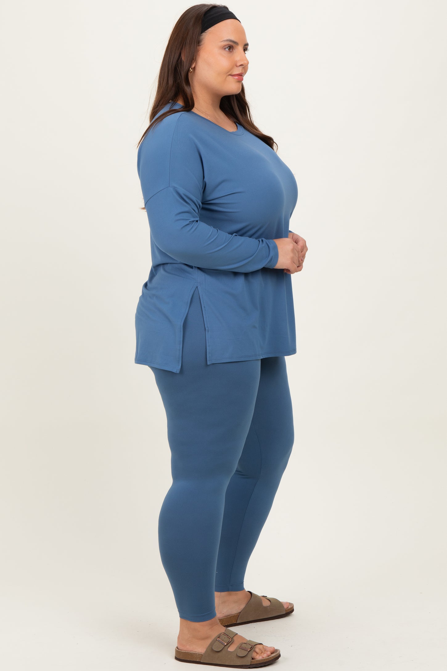 woman wearing a blue long sleeve top with side slits and matching leggings in plus size activewear style