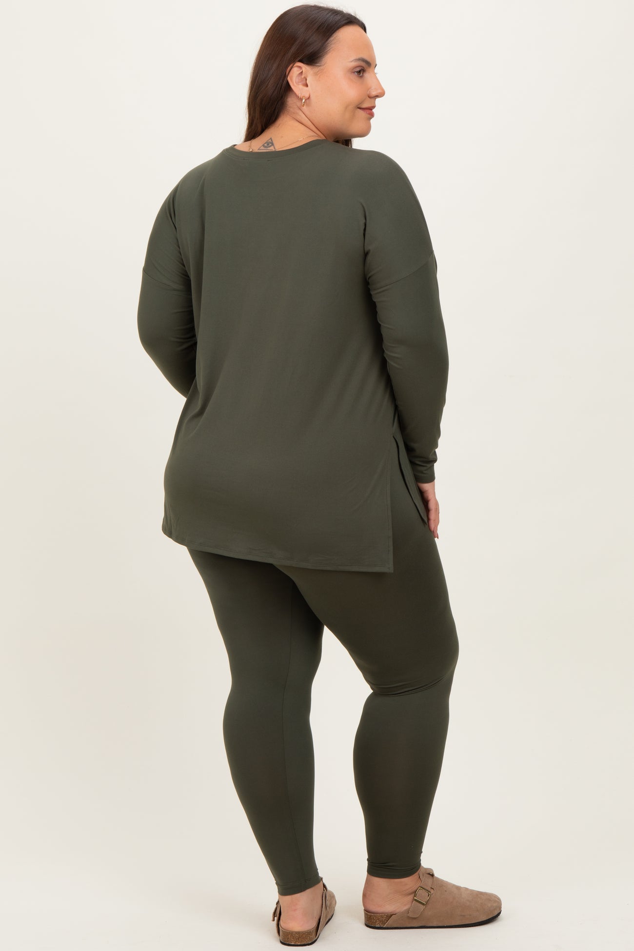 woman wearing an olive green long sleeve top with side slits and matching leggings, viewed from the back
