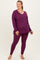 woman wearing a purple long sleeve maternity top and matching leggings, showing off her baby bump