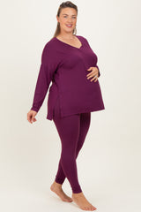 woman wearing a dark purple maternity plus long sleeve top and matching leggings, showing her baby bump