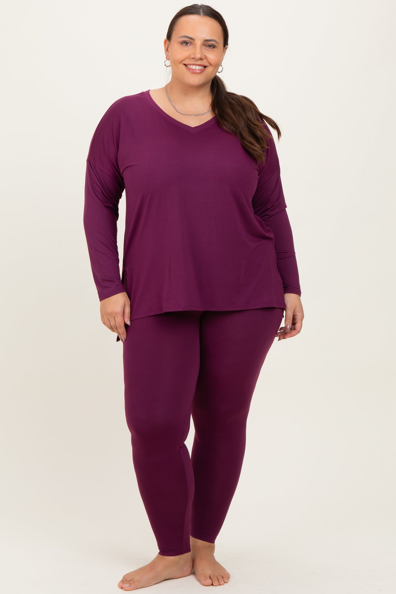woman wearing a purple long sleeve top and matching leggings in plus size, standing with a smile