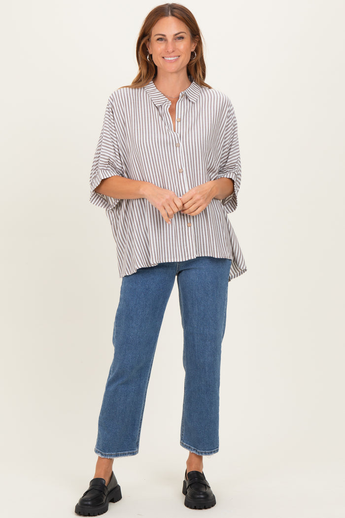 woman wearing a brown and white striped oversized button-up shirt with relaxed fit and blue jeans