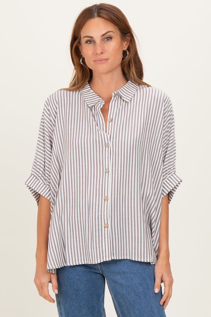 woman wearing a striped button-up shirt with rolled sleeves and relaxed fit, paired with blue jeans