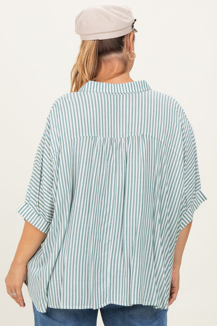 woman wearing a green and white striped maternity plus shirt, featuring a relaxed fit and roll-up sleeves