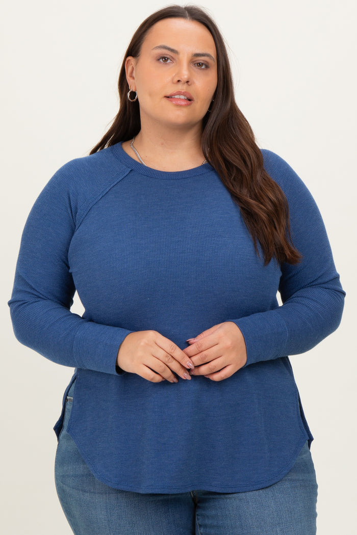 woman wearing a navy blue long sleeve plus size top with a curved hem and side slits