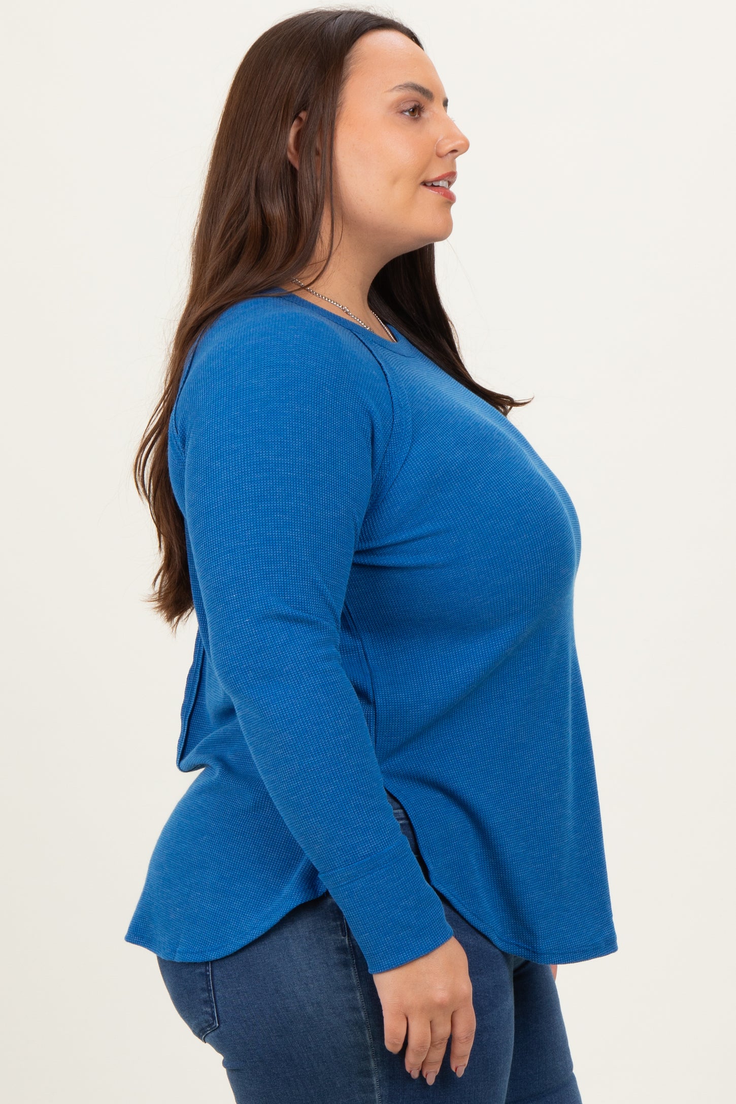 woman wearing a blue long sleeve ribbed top with side slits and relaxed fit paired with denim jeans