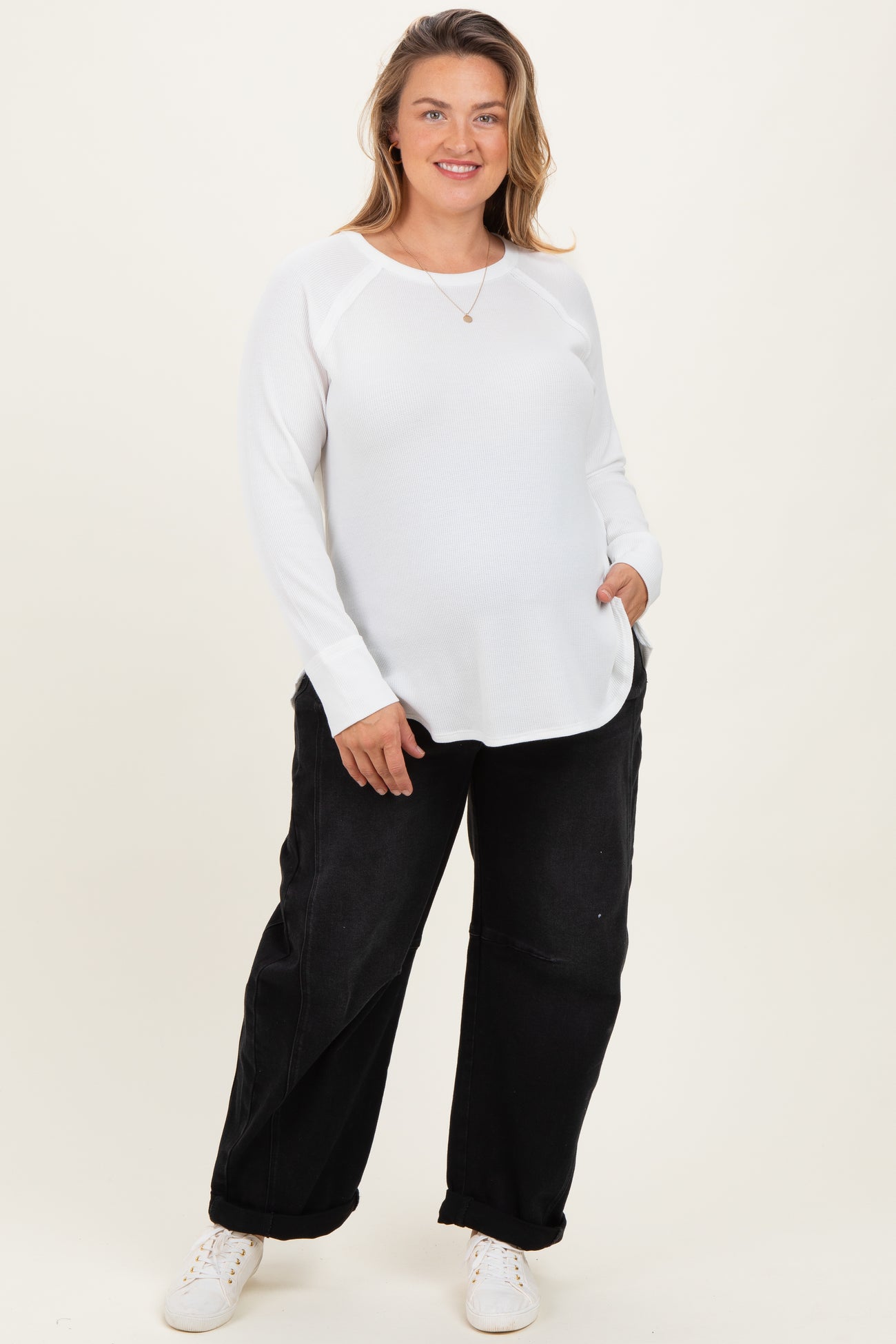 woman wearing a white long sleeve maternity top with pockets and black wide-leg maternity pants