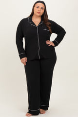 woman wearing a black plus size pajama set with white piping, includes long sleeve button-up top and matching pants