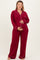 woman wearing a burgundy maternity pajama set with long sleeves and pants, holding her baby bump