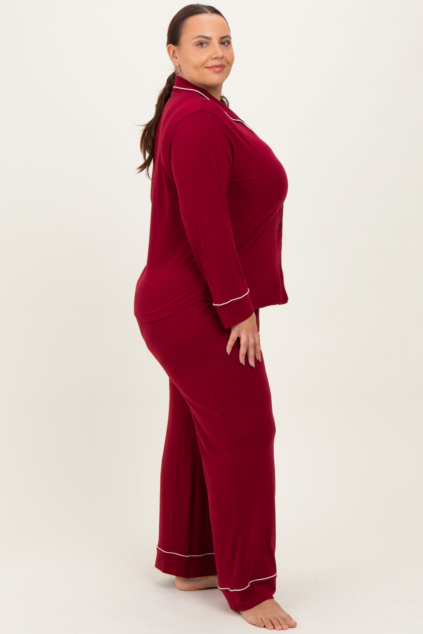 woman wearing a maroon plus size pajama set with white piping details